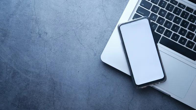 Smartphone und Laptop auf einem Schreibtisch