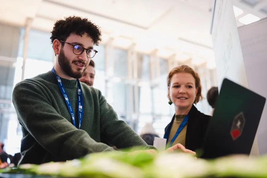 Besucherin und Aussteller am hellen Expo-Stand im Foyer der IHK Berlin.